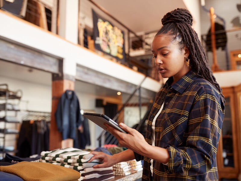 Woman Using Digital Tablet To Check Stock In Clothing Store_Resized