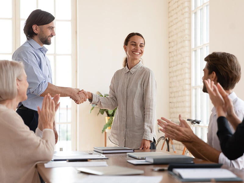 Boss shake hands with successful team member mixed-race proud happy woman during meeting at boardroom