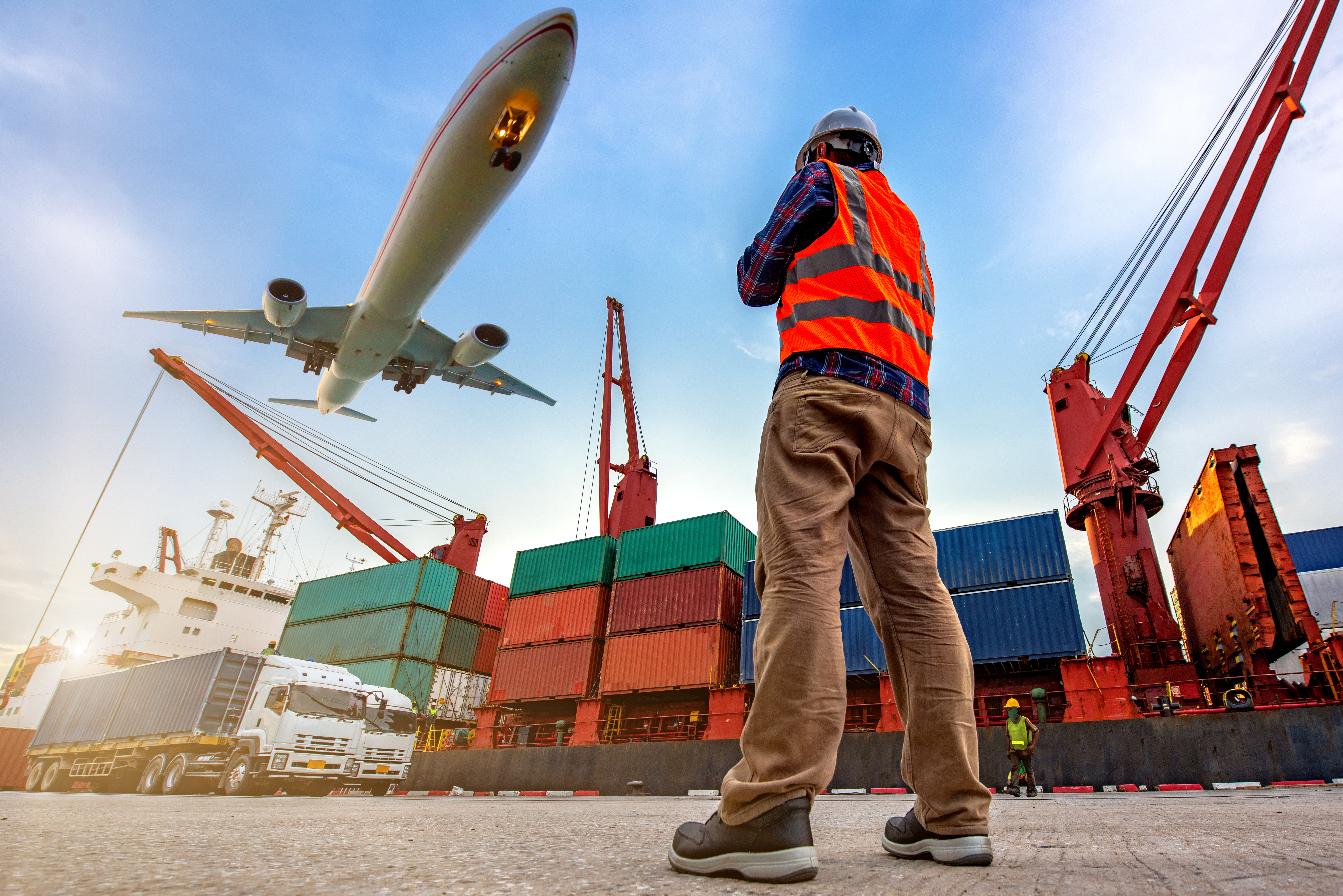 Man standing with containers and airplanes in the background