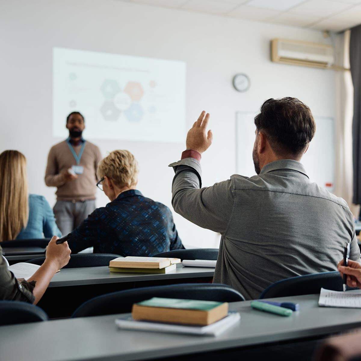 Student raising hand to ask professor a question