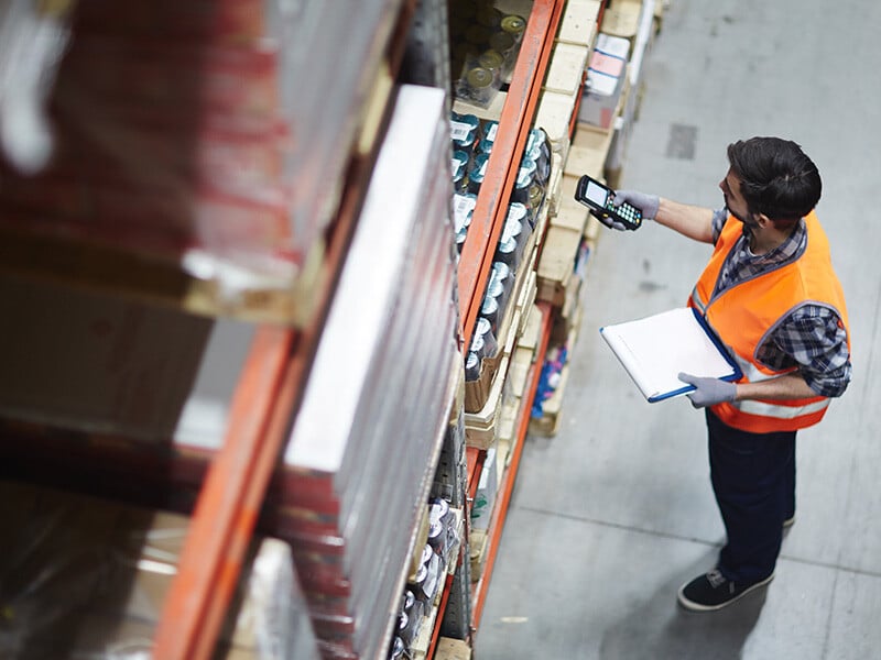 Worker with scanner making review of goods in warehouse